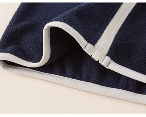 Close-up of navy blue fleece fabric with white zipper detail and stitching for kids set