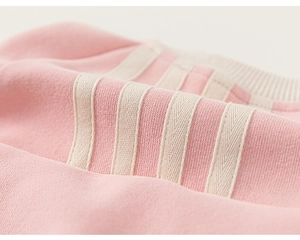 Macro detail of pink girl's hoodie featuring high-quality cotton fabric and cream ribbing