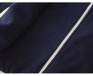 Detail of navy polar fleece fabric texture and contrast white zipper on children jacket