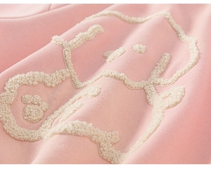 Close-up of pink knit fabric featuring a soft white towel embroidery cartoon design
