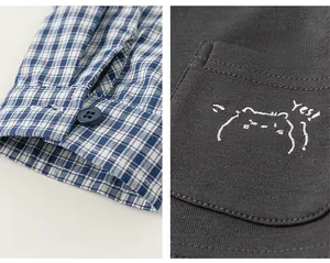 Detailed view of checkered cuffs and cat embroidery on children's casual cotton set