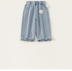 Detailed view of light blue denim wide-leg trousers with lace patches and ruffled hems