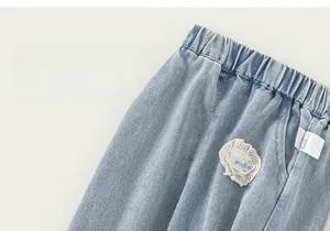 Detail of girls denim jeans with elastic ruched waistband and delicate lace embroidery decoration