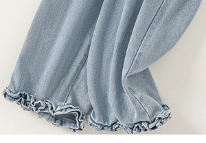 Detailed macro view of light blue denim pants featuring ruffled hems and elastic cuffs