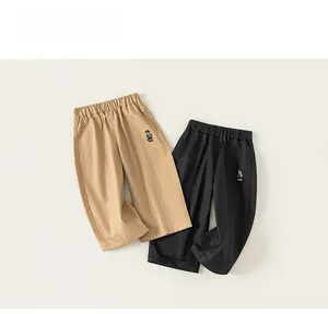 Détail de la taille élastique et broderie ours sur pantalons enfants kaki et noir