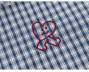 Detailed close-up of blue and white checkered fabric with cute red heart embroidery