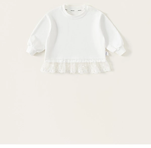 Detailed close-up of white long sleeve kid top with floral lace hem and embroidery details