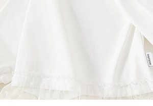 Detail view of white toddler girl shirt featuring floral lace mesh hem and cotton fabric