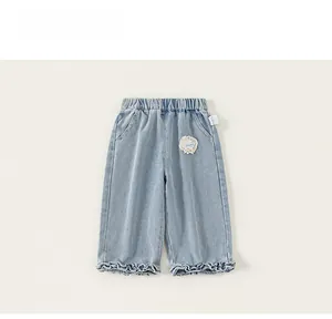 Detail of girls denim trousers with lace embroidery and ruffled leg openings