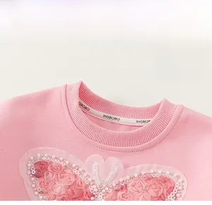 Detail of pink cotton girl sweatshirt showing lace petals, sequins and pearl embroidery