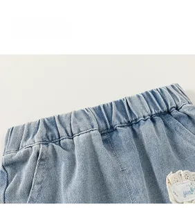 Detail of girls' blue denim jeans featuring an elastic waistband and white lace trim