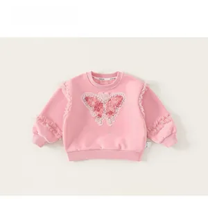 Detail of child's pink sweatshirt featuring large embroidered butterfly and pearl accents
