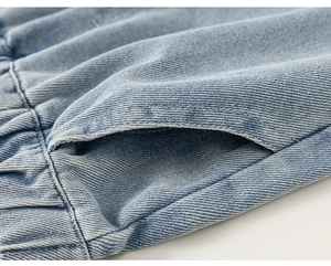 Detailed macro view of light blue denim pants with elastic waistband and side pockets