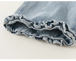 Detailed close-up of light blue denim pants featuring ruffled elastic hem and twill fabric