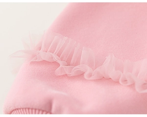 Detailed close-up of soft pink cotton fabric with delicate tulle ruffle trim decoration