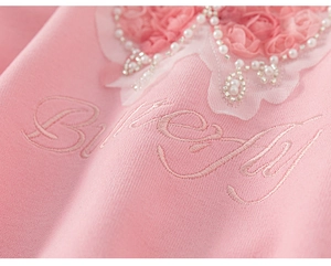 Detail view of pink sweatshirt with pearl, lace heart and Birthday embroidery