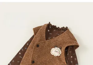 Détail d'un gilet en tricot marron avec décor de lapin et chemise à fleurs bébé