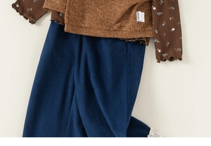 Détail du haut floral à manches longues avec gilet en maille et pantalon en velours