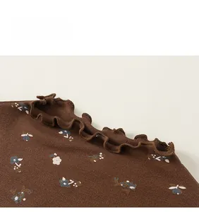 Détail du tissu en maille côtelée marron avec imprimé fleuri et col à volants fille