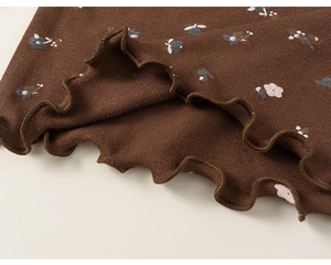 Détail du tissu en maille marron avec motif floral et ourlet à volants pour fillettes