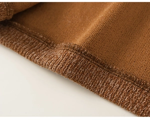 Détail du tissu tricoté couleur camel montrant des coutures fines et une texture douce