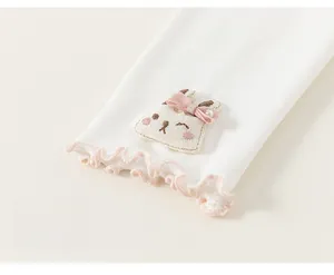 Detailed embroidery of a 3D rabbit patch with pink bow and ruffled lace on kids clothing