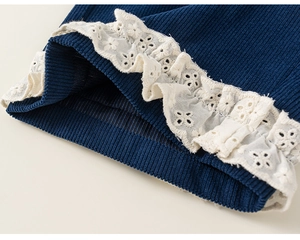 Détail macro de maille côtelée bleu marine avec broderie florale en dentelle blanche