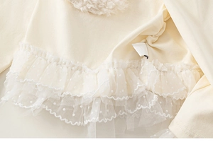 Detail of girls beige long sleeve top with white polka dot mesh ruffles and soft texture