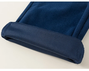Gros plan détaillé montrant l'ourlet replié et la texture côtelée du pantalon en velours