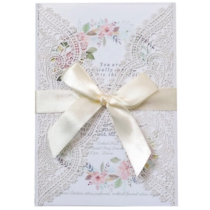 Elegant laser-cut lace wedding invitation with cream white finish and beige silk bow