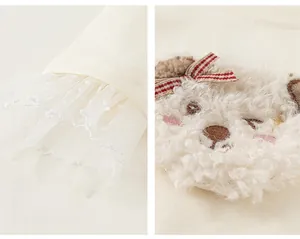 Detail of lace cuffs and a plush puppy applique on the cream-colored long-sleeve T-shirt