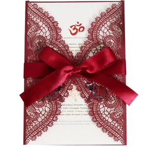 Laser-cut burgundy wedding invitation with lace pattern and matching satin ribbon bow
