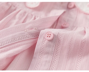 Detailed close-up of pink cotton fabric with embroidery and buttons for baby set