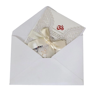 White laser cut lace wedding invitation with beige ribbon bow and om symbol