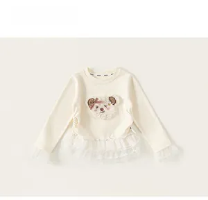 Detail of girls' cream sweatshirt with plush bear patch and delicate lace mesh hem