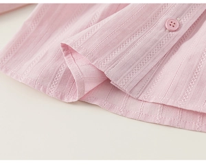 Detailed macro view of pink cotton fabric with vertical embroidery and a four-hole button