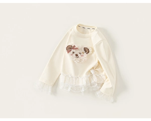 Detailed view of plush teddy bear embroidery and polka dot lace trim on girls' long sleeve top