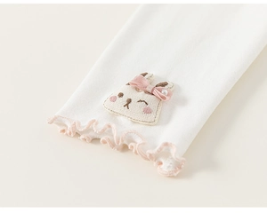 Detailed view of white cotton sleeve with pink ruffled edges and rabbit embroidery
