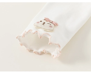 Detail of baby girl outfit showing cotton cuff with pink ruffle and cute cartoon patch
