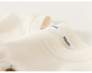 Detailed close-up of the round neckline and stitching on a lace cream toddler T-shirt