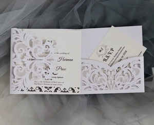 Close-up of laser-cut white wedding invitation with elegant lace hollow patterns and RSVP card