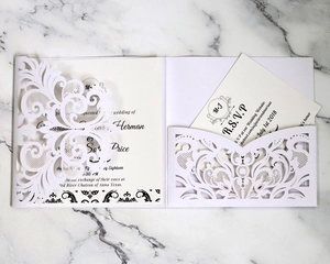 Elegant white laser-cut floral wedding invitation with RSVP card on marble background