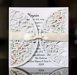 Elegant white laser-cut wedding invitation with butterfly patterns and beige ribbon bow