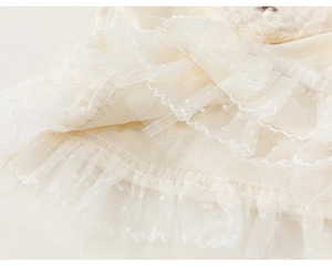Detail of baby girl shirt featuring delicate lace edges and white polka dot mesh fabric