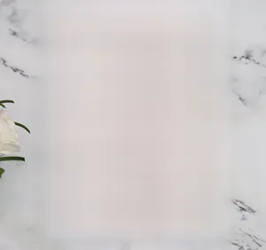 Detail showing a silver glitter laser-cut snowflake invitation sleeve on marble background