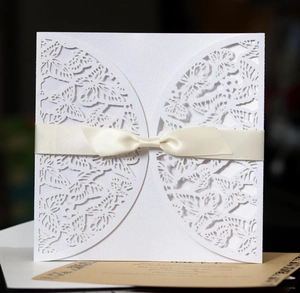 Elegant white laser-cut wedding invitation featuring butterfly hollow design and cream ribbon