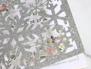 Macro shot of silver glitter laser-cut snowflake invitation cover with intricate details