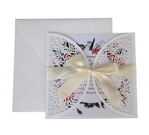 Detailed laser cut wedding invitation with cream satin bow and floral inner page