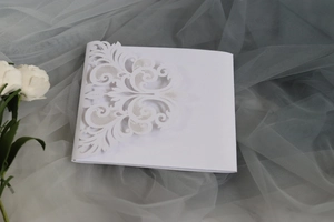 Close-up of laser cut floral lace details on elegant white wedding invitation card