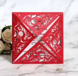 Detailed close-up of red laser-cut wedding invitation with baroque pattern on marble surface